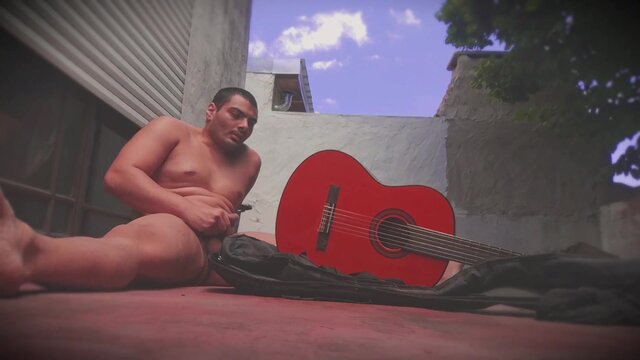 Muscular man rubs massive dick against guitar in outdoor solo act